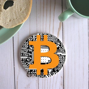 May include: A round coaster with a black and white circuit board design and an orange Bitcoin symbol in the center.