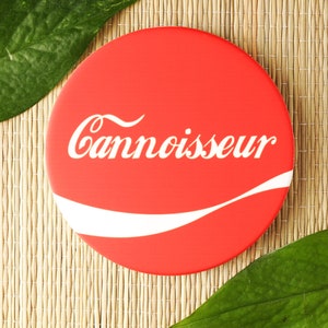Puede incluir: Posavasos redondo rojo y blanco con la palabra "Cannisseur" en letras blancas.