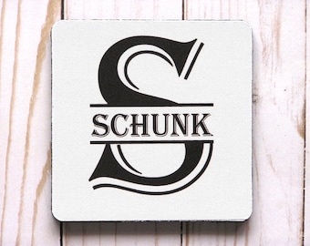May include: A white square coaster with a black letter "S" and the name "SCHUNK" printed in black.