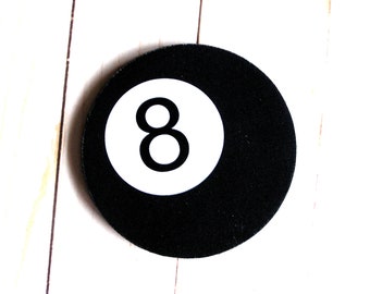 May include: A black and white billiard ball with the number 8 printed in white on a white circle in the center of the ball.
