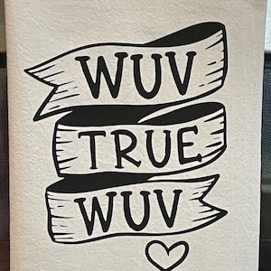 May include: White kitchen towel with black text that reads "WUV TRUE WUV" in a banner design, with a heart symbol below. The towel is made of a soft, textured fabric.