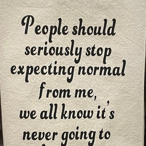 May include: Off-white kitchen towel with black text that reads: "People should seriously stop expecting normal from me, we all know it's never going to happen."