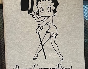 Op de afbeelding: Witte stof met een zwarte illustratie van Betty Boop met een hoge hoed en wandelstok. De tekst "Boop-Oop-a-Doop!" staat eronder in een cursief lettertype. Een klassiek cartoonontwerp.