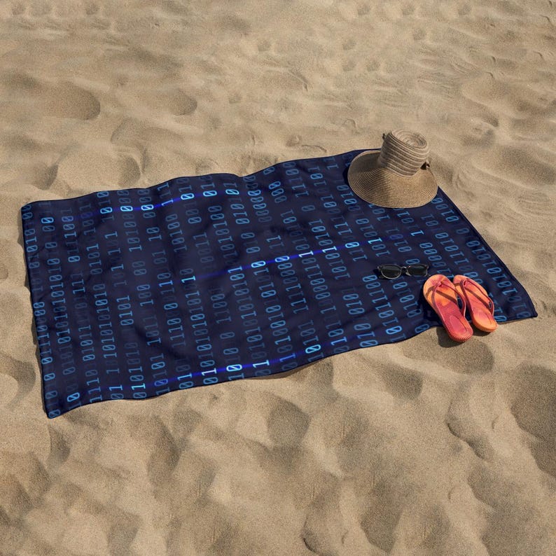 May include: A navy blue beach towel with a binary code pattern, a straw hat, sunglasses, and orange flip-flops on a sandy beach. The towel is rectangular and has a repeating pattern of blue binary digits.