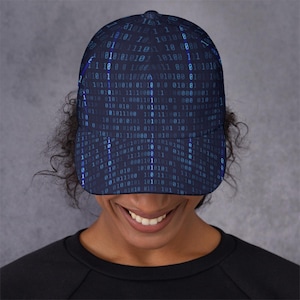 May include: A navy blue baseball cap with a repeating binary code pattern in blue and teal. The cap has a curved peak and a structured crown, offering a modern, tech-inspired aesthetic.