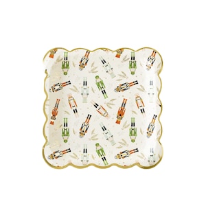 May include: White paper party plates with a gold scalloped edge and a repeating pattern of colourful nutcracker figurines on a white background.