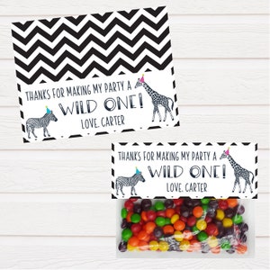 May include: Black and white chevron patterned favour bags with a white tag that says "Thanks for making my party a wild one! Love, Carter" and a zebra and giraffe wearing party hats.