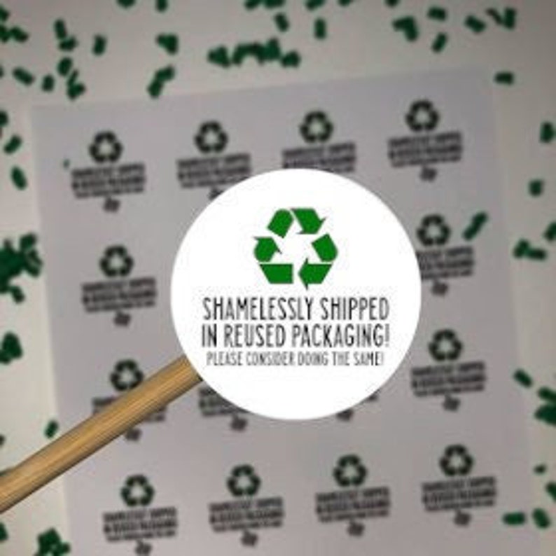 Op de afbeelding: Een ronde witte sticker met een groen recycle-symbool en de tekst "Schaamteloos verzonden in hergebruikte verpakking! Overweeg om hetzelfde te doen."