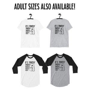May include: Four t-shirts featuring a ghost holding a bag of sweets and the text "It's Tricky" repeated five times. Two t-shirts are white with black sleeves and two t-shirts are grey with black sleeves.