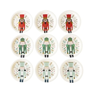 May include: Set of eight white paper plates with a festive Nutcracker theme. Each plate features a different illustration of a Nutcracker soldier in red and green uniforms with gold accents. The plates are perfect for a holiday party or special occasion.