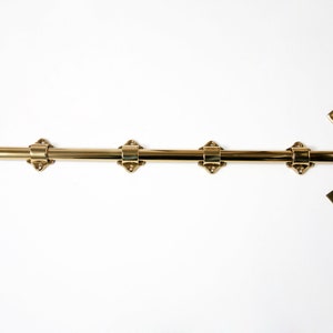 May include: A polished brass surface bolt with a round knob and four decorative diamond-shaped mounts. Includes a strike plate and a loop for a padlock. Hardware for doors and gates.