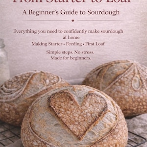Könnte beinhalten: Drei runde Sauerteigbrote, eines mit einem herzförmigen Design. Der Text lautet: "From Starter to Loaf, A Beginner's Guide to Sourdough." Der Leitfaden enthält Video-Tutorials und ist für Anfänger gedacht.
