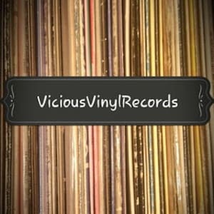 Puede incluir: Primer plano de una pared de discos de vinilo con un letrero negro que dice "Vicious Vinyl Records".