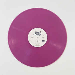 Puede incluir: Un disco de vinilo morado liso con una etiqueta blanca en el centro. La etiqueta presenta el texto "Manic Halsey" y otros textos y s&iacute;mbolos peque&ntilde;os. El disco es circular y est&aacute; sobre una superficie blanca.