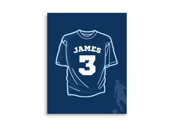 May include: A blue t-shirt with the name "JAMES" and the number "3" printed on the back. The t-shirt is on a dark blue background.