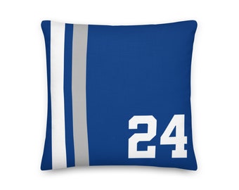 May include: A square throw pillow in royal blue featuring a vertical white stripe and a vertical grey stripe on the left side. The number 24 is printed in large, bold white block lettering on the right side of the blue pillow surface.