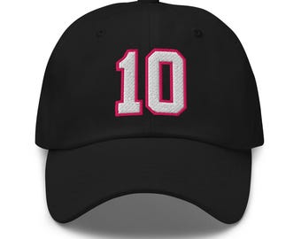 May include: Black baseball cap with a white number 10 embroidered in pink on the front.
