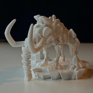 Op de afbeelding: Een witte 3D-geprinte sculptuur van een mammoetskelet. De sculptuur heeft gebogen slagtanden, een gedetailleerde schedel en gelede poten. De mammoet staat op een getextureerde basis, met een prehistorisch thema.