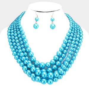 May include: A multi-strand necklace featuring five rows of glossy, bright turquoise blue faux pearls of varying sizes, paired with matching drop earrings that each consist of two stacked turquoise blue faux pearls on gold-tone metal hooks.