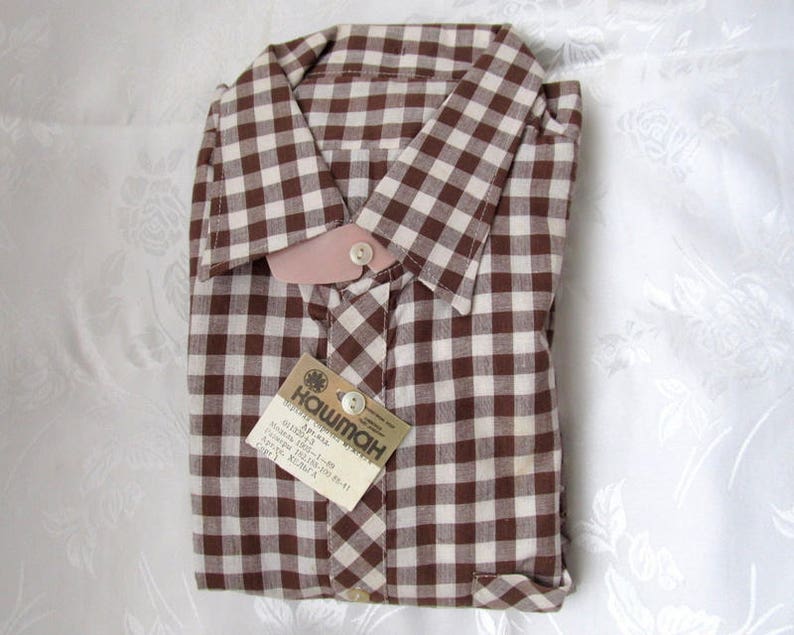 May include: A brown and white gingham button-down shirt with a tag that reads "Hawiman" and "Art. 4914".
