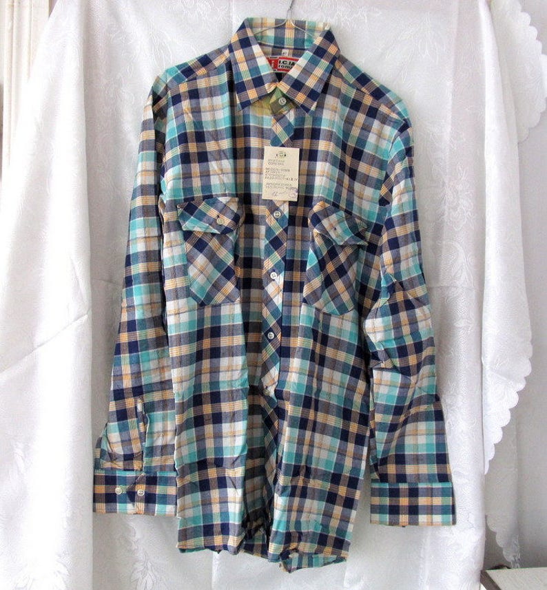 May include: A long-sleeved plaid shirt with a blue, green, yellow, and white checkered pattern. The shirt has two chest pockets and a button-down collar. The shirt has a tag that reads "I.C.M. Industries, Inc."