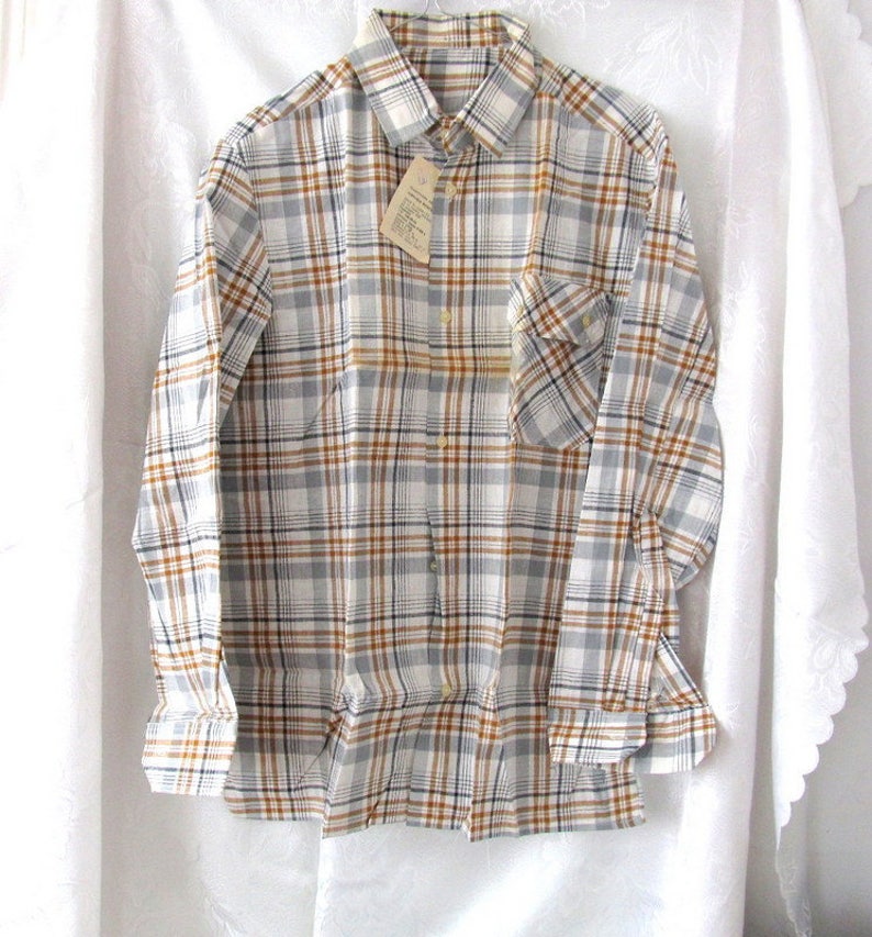 May include: A long-sleeved plaid shirt with a white, brown, and blue plaid pattern. The shirt has a button-down collar and a single chest pocket.