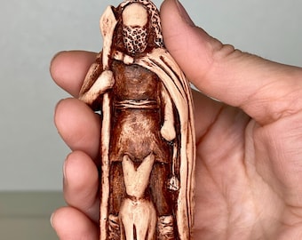 May include: A hand-painted ceramic figurine of a man with a beard and a cloak, holding a staff. A dog is at his feet. The figurine is brown and white.