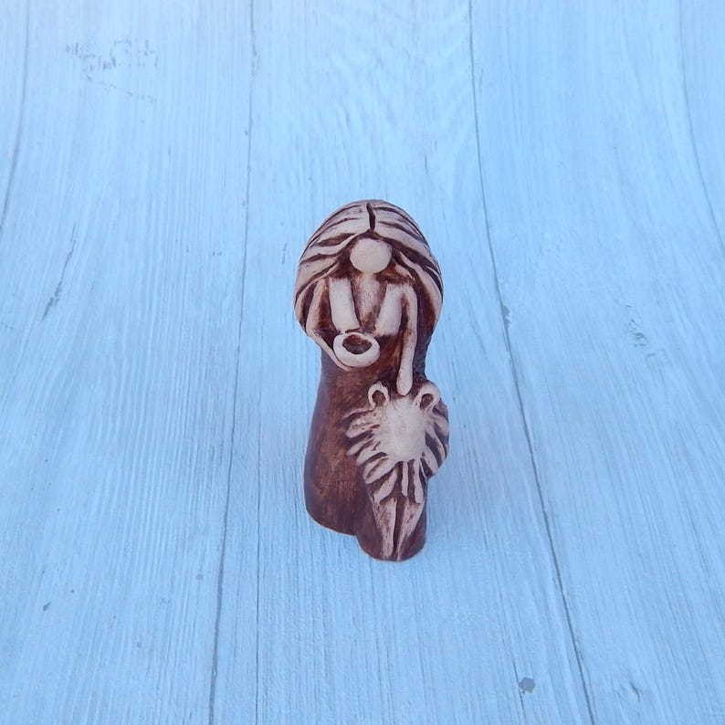 May include: A ceramic figurine of a woman with long hair and a lion cub. The figurine is painted in brown and white.
