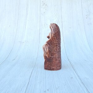 May include: A terracotta sculpture of a woman holding a child. The sculpture is brown and has a rough texture.
