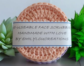 May include: Two crocheted face scrubbies in peach and lavender colors. The scrubbies are handmade and have a label that reads "Re-useable Face Scrubbies Handmade with Love by EmilyLouCreations".