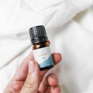 May include: A small brown glass bottle with a black cap and a white label that says "EMBYR Chillax 5 ml / 0.17 fl oz".