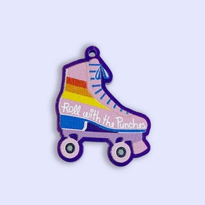 May include: A pink roller skate with rainbow stripes and the text "Roll with the Punches" on the side. The skate has purple wheels and a blue strap.
