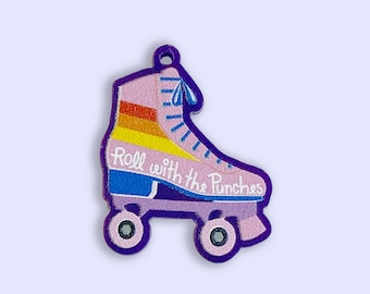 May include: A pink roller skate with rainbow stripes and the text "Roll with the Punches" on the side. The skate has purple wheels and a blue strap.