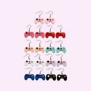 May include: A set of 12 pairs of colorful video game controller earrings. Each pair features a different color, including pink, red, blue, green, white, and black.