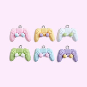 May include: Six pastel-colored plastic game controller charms. The charms are in pink, yellow, white, green, blue, and purple. Each charm has a silver loop for hanging.