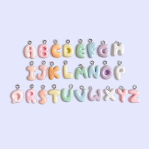 May include: A set of 26 pastel-colored letter charms, each with a silver loop for attaching to a necklace, bracelet, or other jewelry. The letters are arranged in alphabetical order, with each letter a different color.