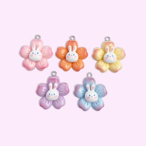 Puede incluir: Cinco encantos de flores de cerámica con caras de conejito. Las flores son en tonos de rosa, naranja, amarillo, morado y azul.