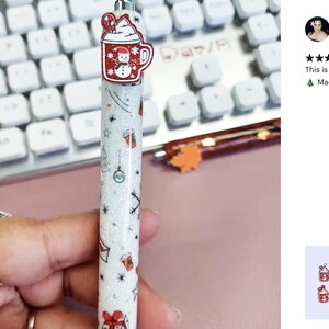 May include: A white glitter pen with a red and white snowman design on the top. The pen has a variety of Christmas-themed designs, including a snowman, a Christmas tree, and a gift box.