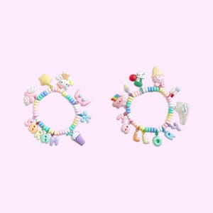 Peut inclure: Deux bracelets en perles color&eacute;es avec des breloques. Un bracelet &eacute;pelle "DREAM" et l'autre "MELODY". Les breloques comprennent une licorne, une &eacute;toile, un nuage, un milk-shake, un cornet de glace, un champignon, un cochon et un c&oelig;ur.