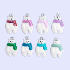 Puede incluir: Ocho dijes de oso polar blanco con bufandas brillantes en rojo, rosa, rosa claro, morado, verde, azul oscuro, azul brillante y verde claro. Cada oso tiene una argolla de metal plateado para colgar, ojos negros y nariz negra.