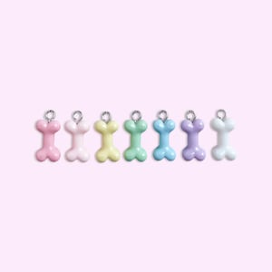 May include: Seven pastel-colored bone-shaped charms with silver rings. The charms are pink, white, yellow, green, blue, lavender, and white.