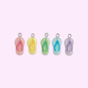 May include: Five colorful flip-flop charms with silver jump rings. The charms are pink, yellow, green, blue, and purple.