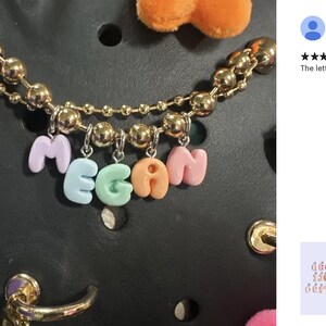 Peut inclure: Une cha&icirc;ne en or avec des breloques en lettres color&eacute;es qui &eacute;pellent le nom "Megan". Les breloques sont faites d'un mat&eacute;riau doux et de couleur pastel.