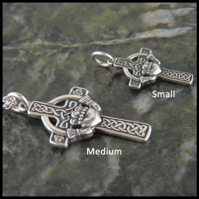 May include: Two silver Celtic cross pendants with a shamrock and a claddagh design. The smaller pendant is labeled "Small" and the larger pendant is labeled "Medium".