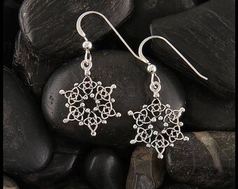 May include: Silver snowflake earrings with a Celtic knot design. The earrings are hanging from silver hooks.