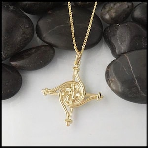 May include: A gold Celtic knot pendant necklace with a four-pointed star design. The pendant is intricate and detailed, with a spiral pattern.