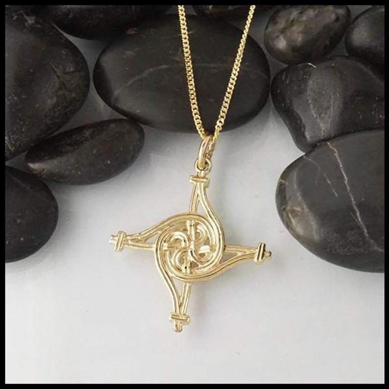 May include: A gold Celtic knot pendant necklace with a four-pointed star design. The pendant is intricate and detailed, with a spiral pattern.
