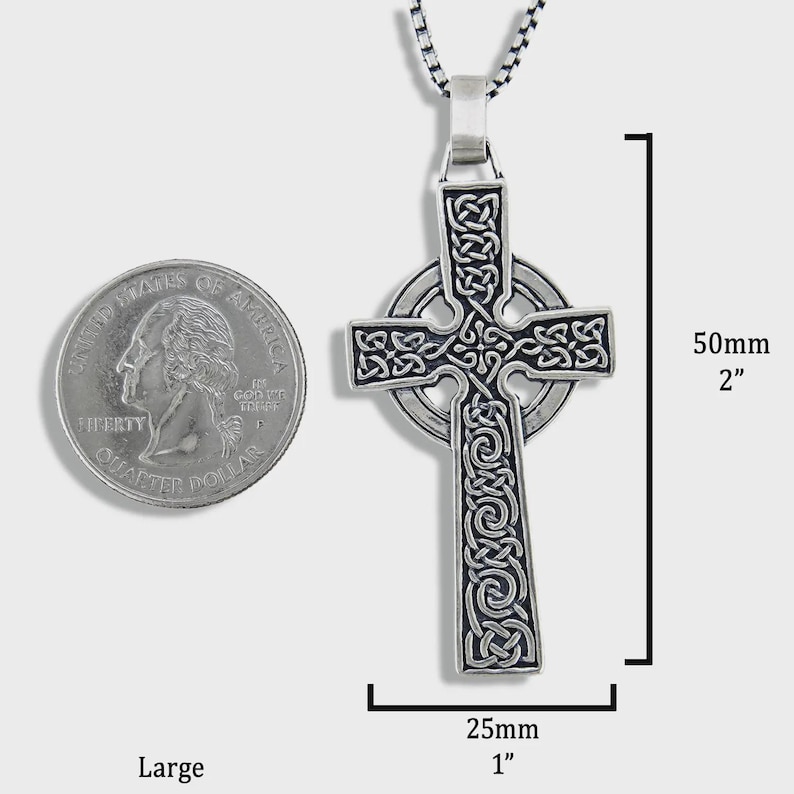 May include: A silver Celtic cross pendant featuring detailed knotwork. The pendant measures 50mm in length and 25mm in width. The cross hangs from a silver chain. A quarter coin is shown for scale.