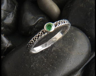 May include: A silver ring with a Celtic knot design and a single green gemstone.