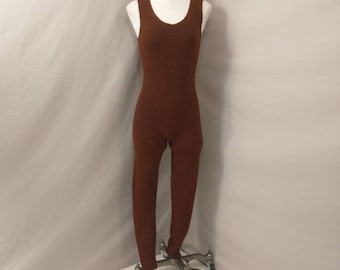 Peut inclure: Combinaison marron une pièce sur mannequin. Le vêtement sans manches a une encolure arrondie. Le tissu semble texturé. Le mannequin est sur un support à roulettes, sur fond neutre.